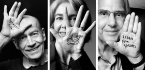 Three scientists holding up their hands, which have written words on the palms