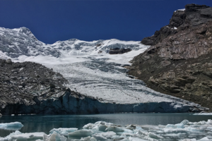 Largely melted glacier nestled between rock with a body of water in front