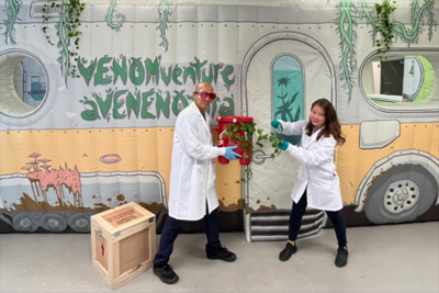 Two people in white lab coats at the entrance of "VenomVenture" escape room
