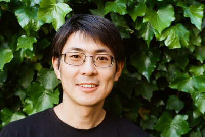 Headshot of Lin Lin, wearing glasses and a black shirt in front of an ivy leaf background