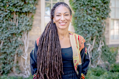 Portrait of woman with long dark twists and a colorful jacket over a black shirt