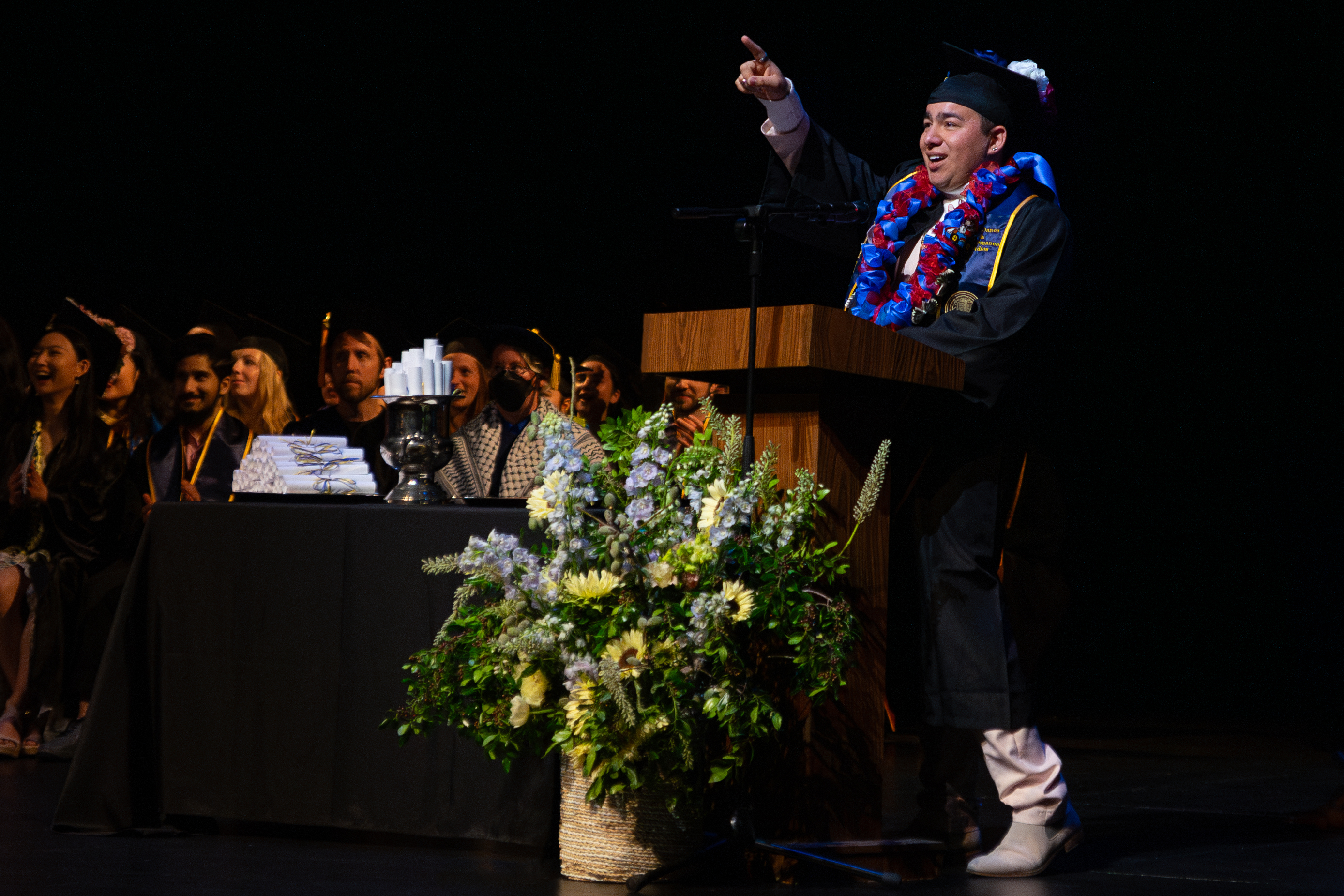 Graduate speaker points at audience during commencement