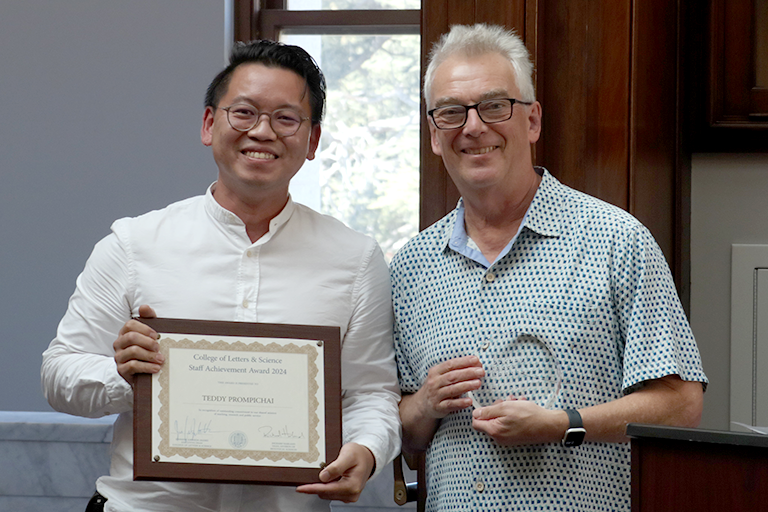 Two men stand together, holding awards